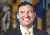 Close up of Russ Kavalhuna, president-elect of Western Michigan University, wearing a dark suit, white shirt and a yellow tie