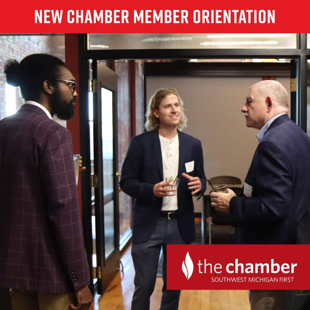 three business people (one diverse) are holding drinks while talking at a work event